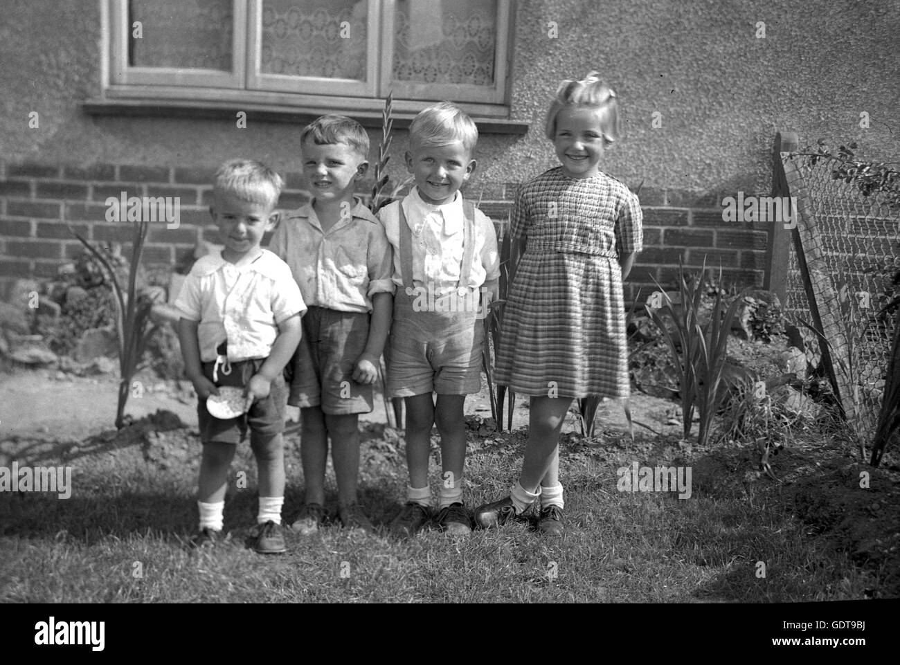 1940s, storico, quattro giovani bambini sorridenti stare insieme in una linea esterna, Inghilterra. Foto Stock