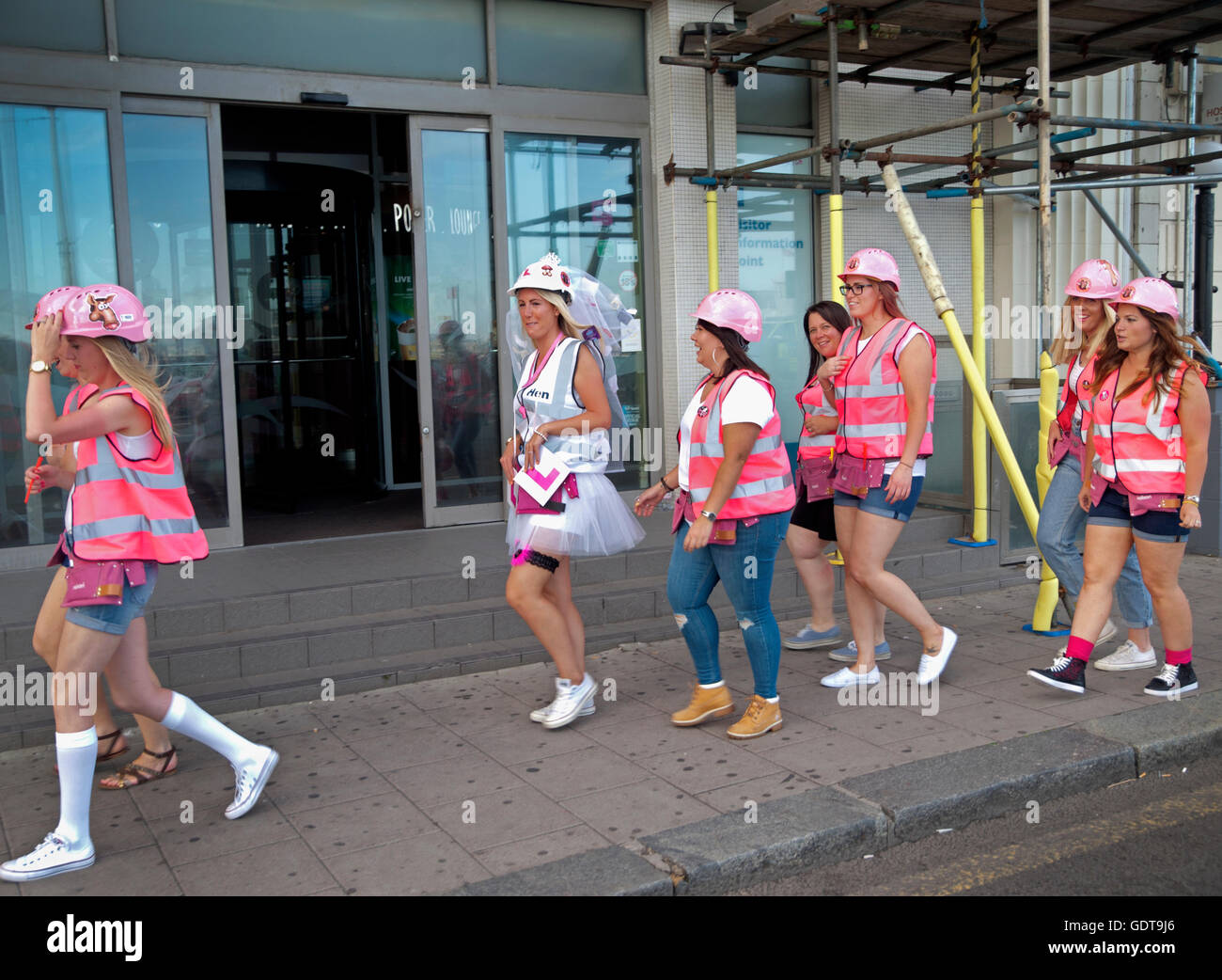 Un partito di gallina, intorno a tema i vestiti di costruttori passeggiate lungo una strada di Brighton Foto Stock
