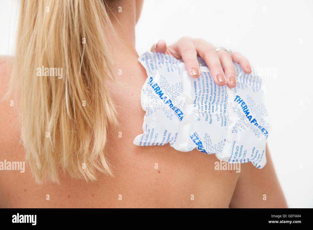 Sostegno femmina Thermafreeze una confezione di ghiaccio sulla sua spalla per aiutare con il dolore e il disagio Foto Stock