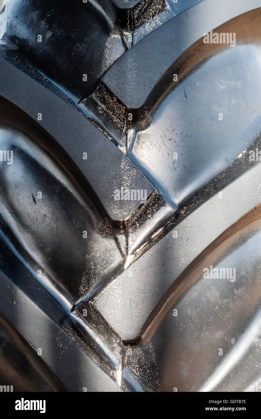 primo piano di un grande pneumatico nero per trattori con nuovi e grandi battistrada in gomma, questo pesante ha un aspetto potente Foto Stock