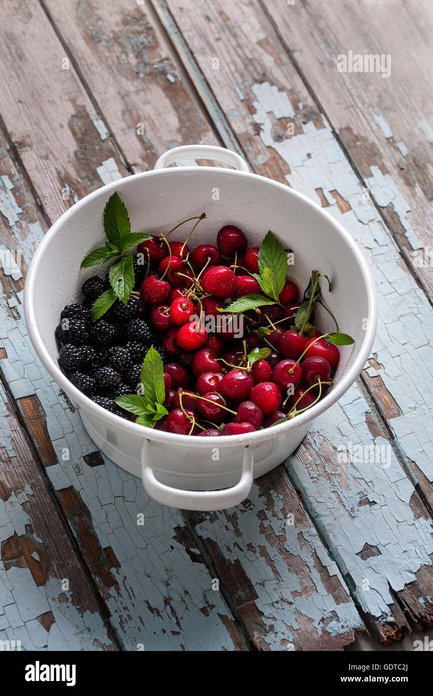 Materie frutta estiva in uno scolapasta su un vecchio tavolo Foto Stock