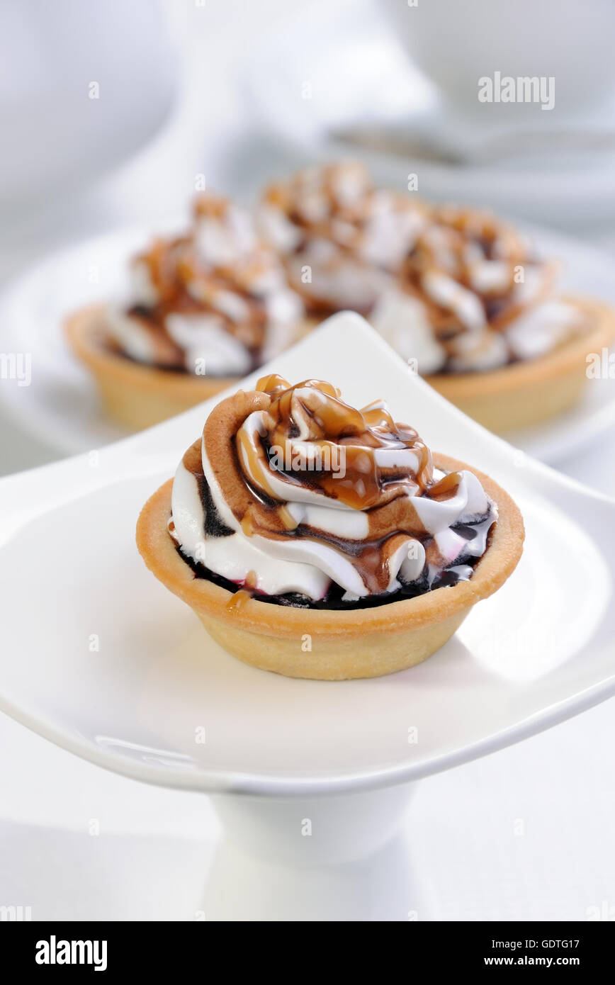 Frollini сakes inceppamento riempiti con panna e cioccolato topping caramel Foto Stock