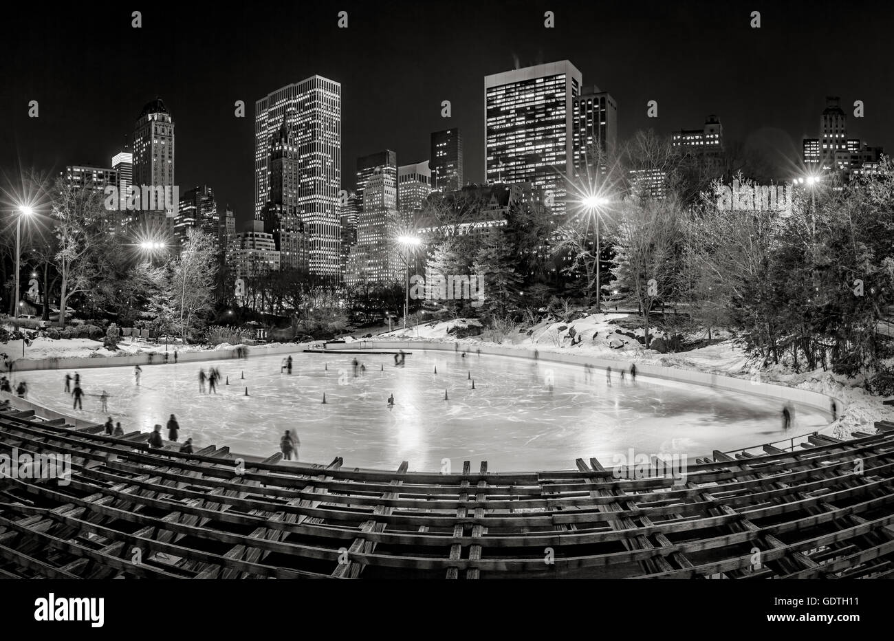 Wollman pista di pattinaggio in Central Park con Midtown Manhattan grattacieli di notte in bianco e nero. La città di New York Foto Stock