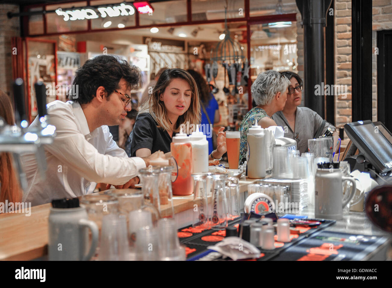 Diners Godetevi il pranzo presso uno dei numerosi prodotti alimentari locali e ristoranti al mercato Sarona a Tel Aviv, Israele Foto Stock