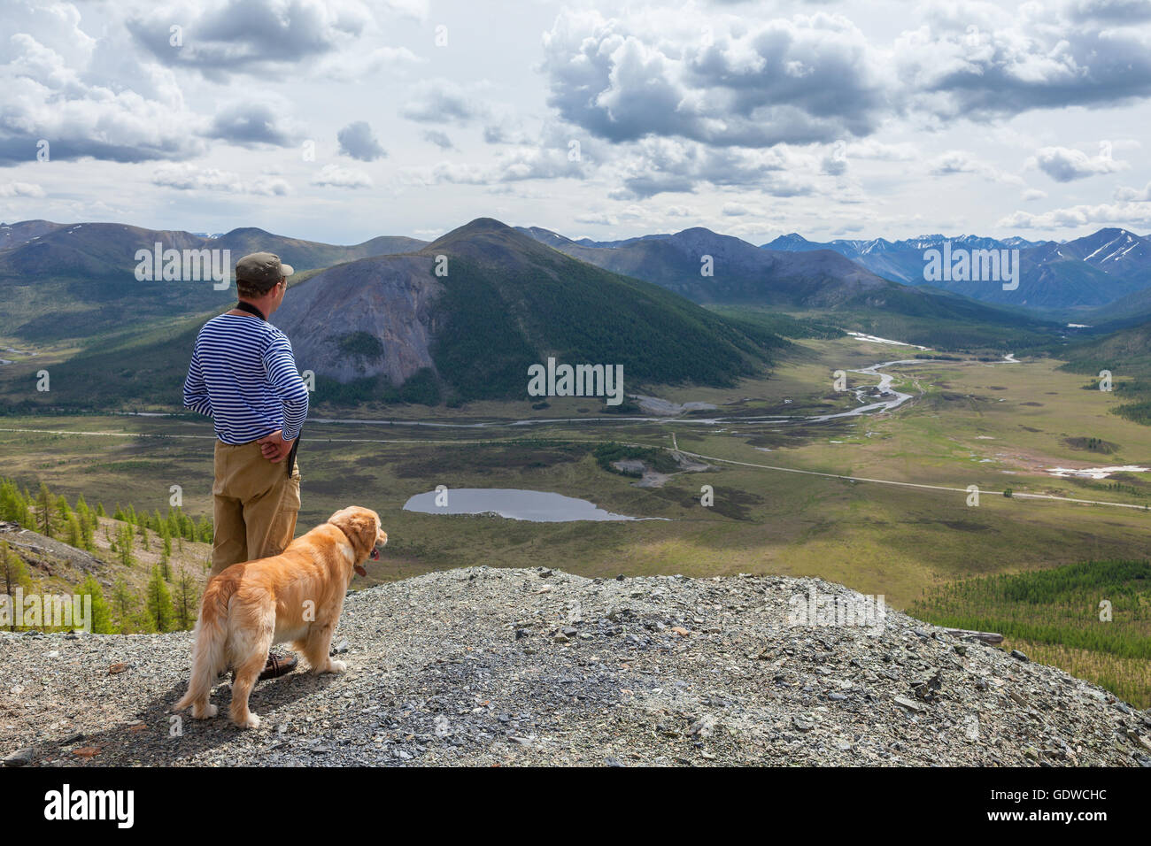 L uomo e il suo cane ammirare il paesaggio di montagna Foto Stock