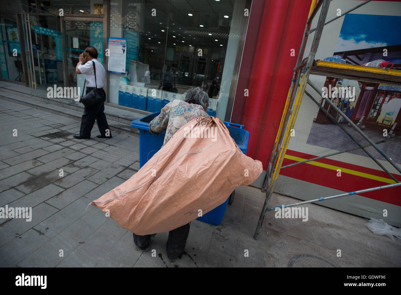 Vecchia donna controllare gli scomparti per le cose a rivendere in Shitou e Dashilar hutong area, a Pechino, in Cina. Foto Stock