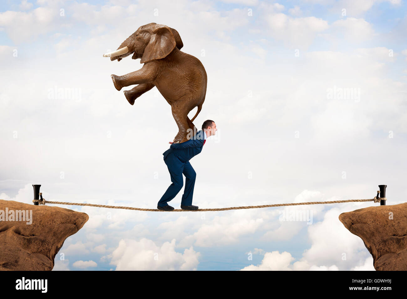 Sfida aziendale imprenditore concetto portante un elefante in una voragine tightrope Foto Stock