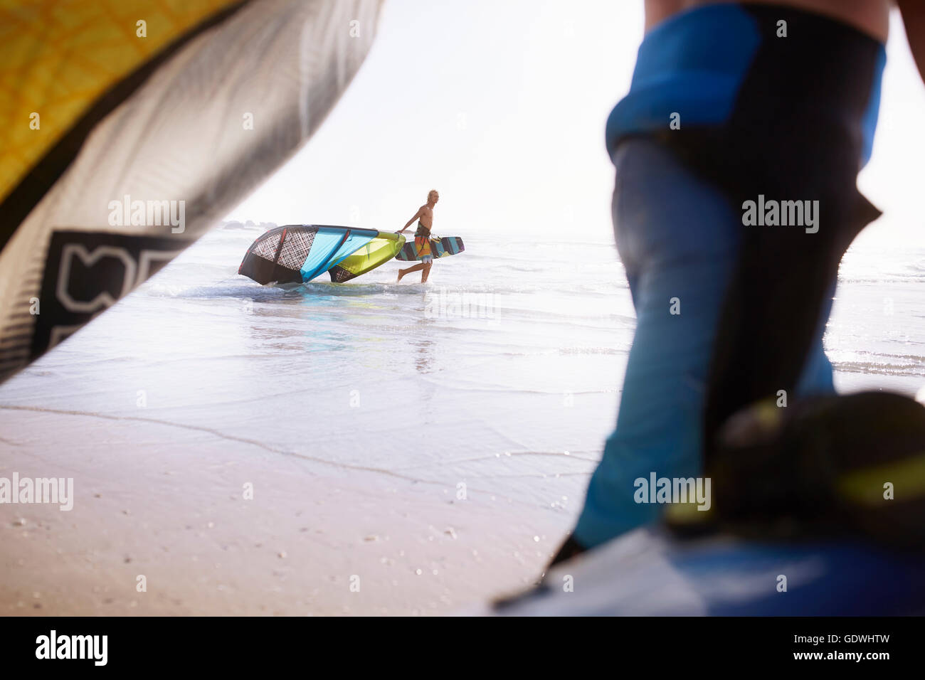L'uomo tirando kiteboarding apparecchiatura a ocean surf Foto Stock