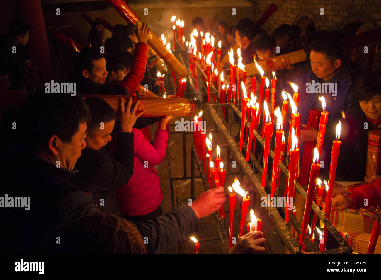 I fedeli accendono le candele in un tempio taoista al quinto giorno del Capodanno cinese Foto Stock