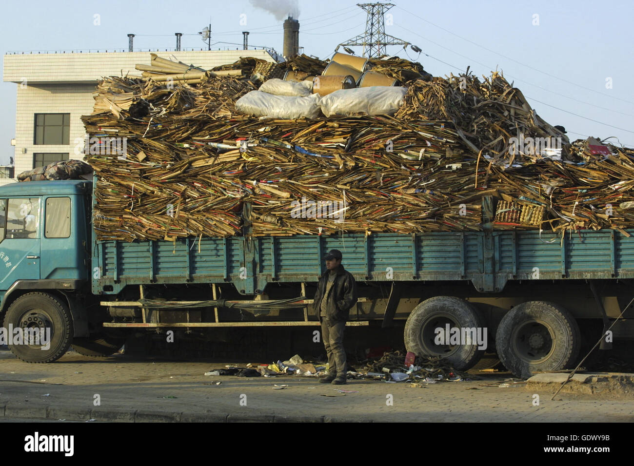 Un uomo si erge oltre ad un autocarro caricato con utilizzata carta cartone Foto Stock