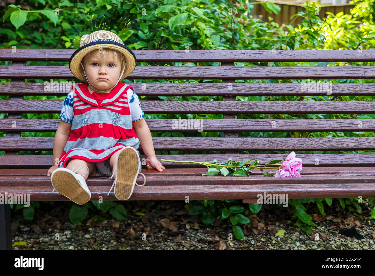 Carino seduta su una panchina toddler cercando grumpy Foto Stock