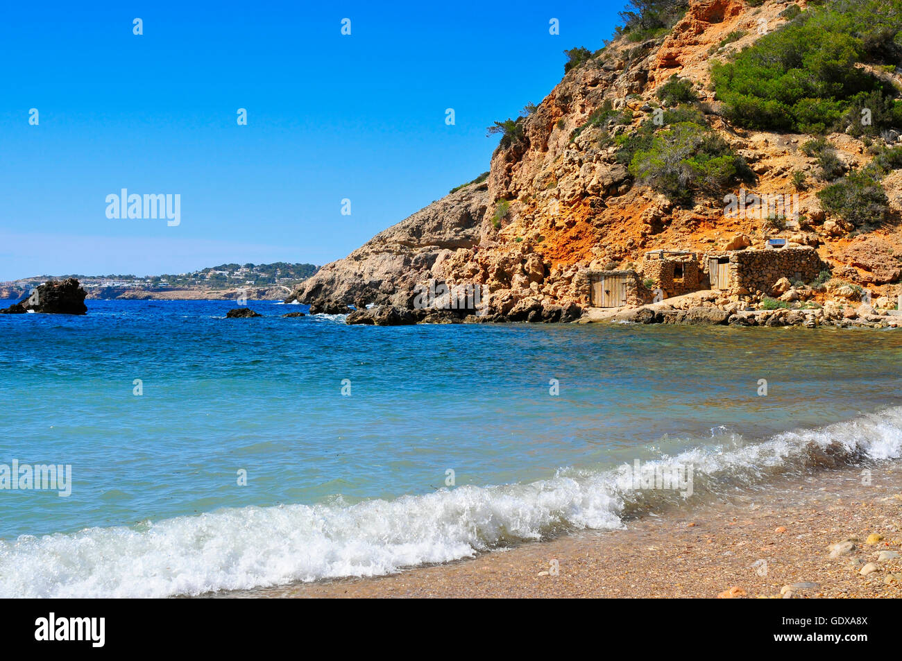 Una vista di una baia solitaria nell isola di Ibiza, Spagna, con alcuni pescatori tradizionali rifugi Foto Stock