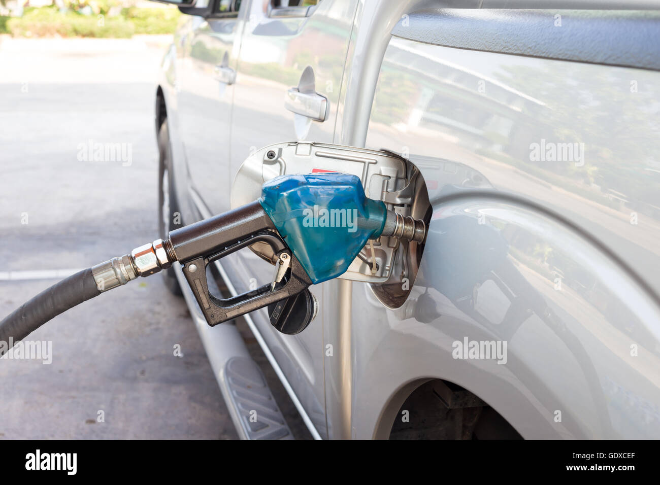 Pompa a gas ugello blu nel serbatoio del carburante di un bronzo auto. Foto Stock
