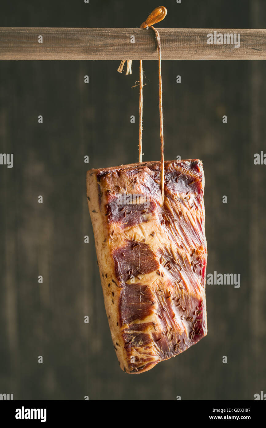 Fresca bacon affumicato appeso sul bastone di legno. Foto Stock