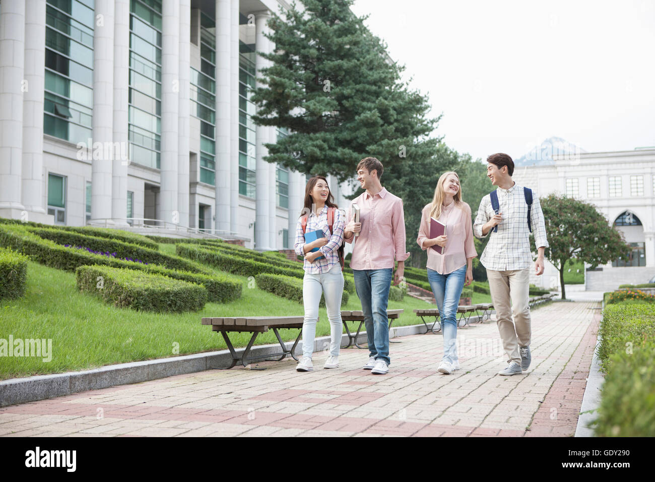 Sorridente quattro studenti del college a piedi faccia a faccia in un campus Foto Stock