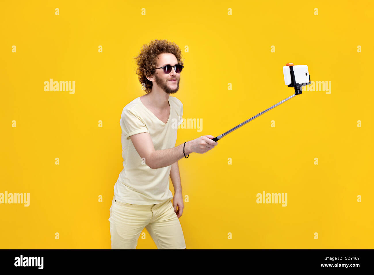 Elegante curly-uomo dai capelli tenendo selfie con monopiede Foto Stock