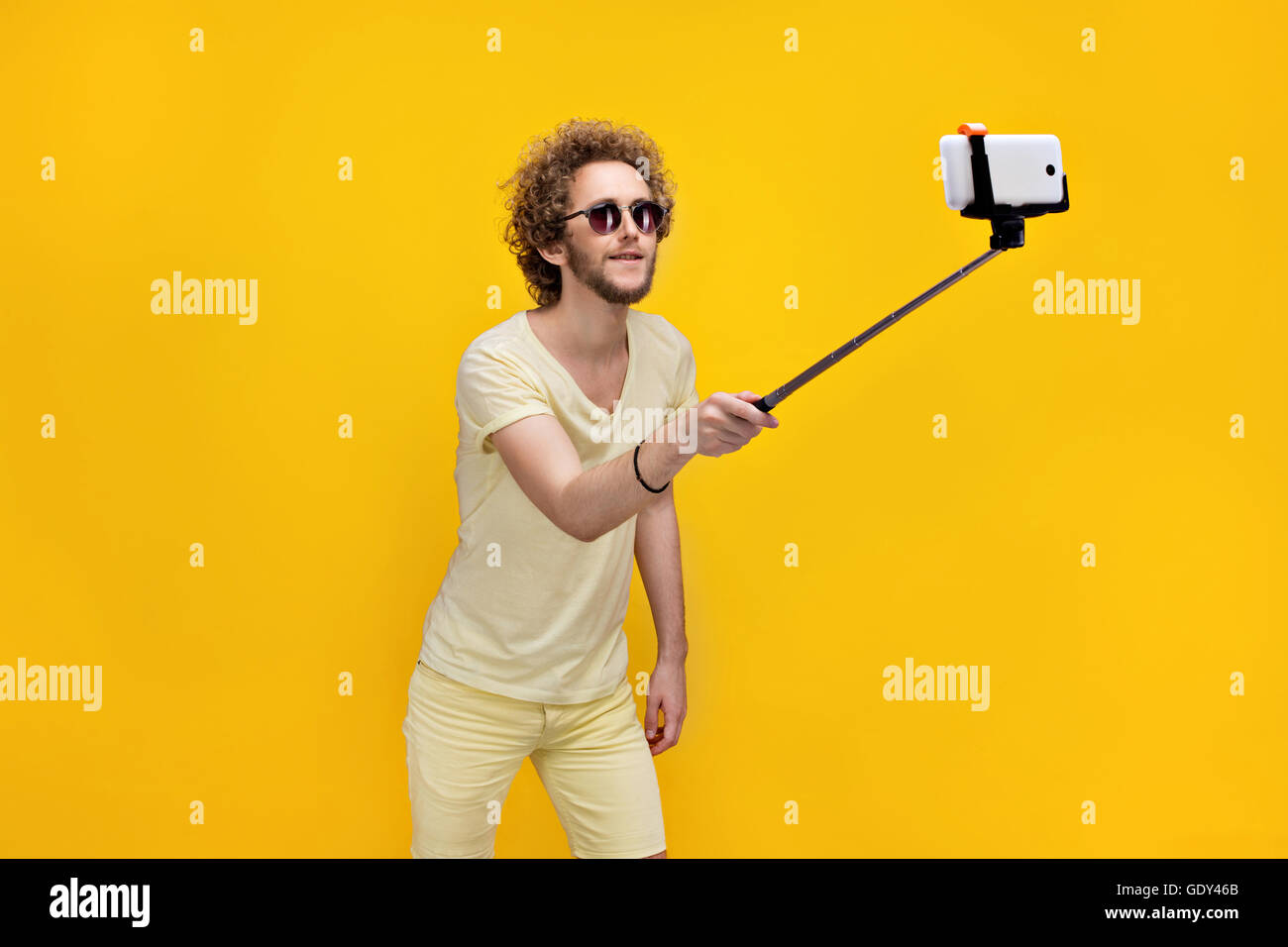 Elegante curly-uomo dai capelli tenendo selfie con monopiede Foto Stock