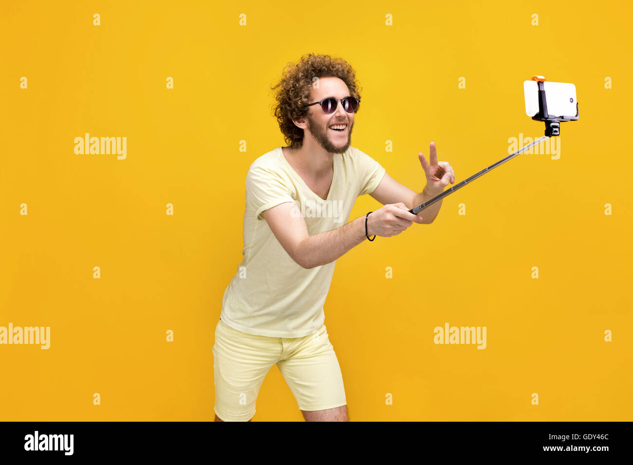 Elegante curly-uomo dai capelli tenendo selfie con monopiede Foto Stock