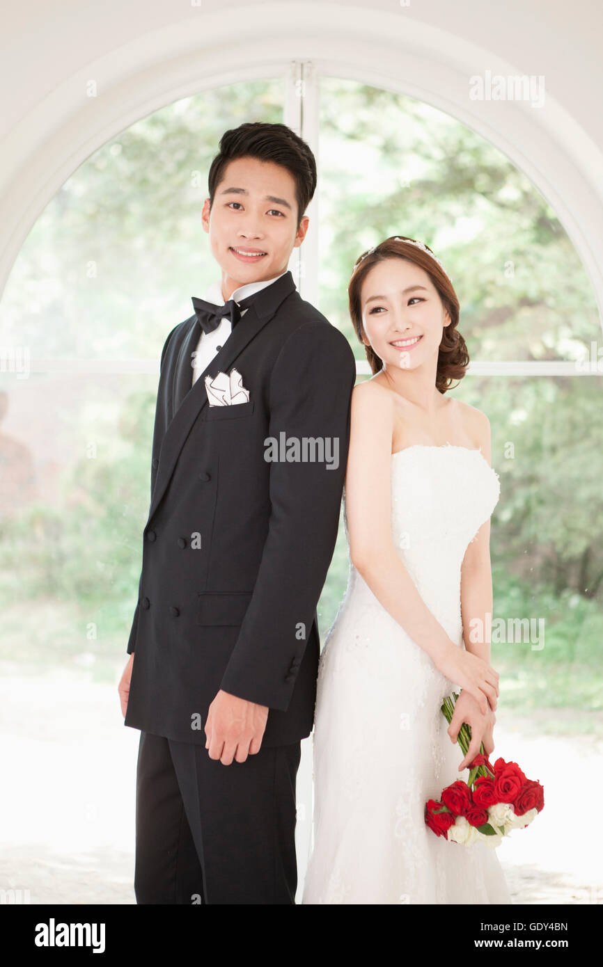 Sorridenti sposi in piedi di schiena Foto Stock