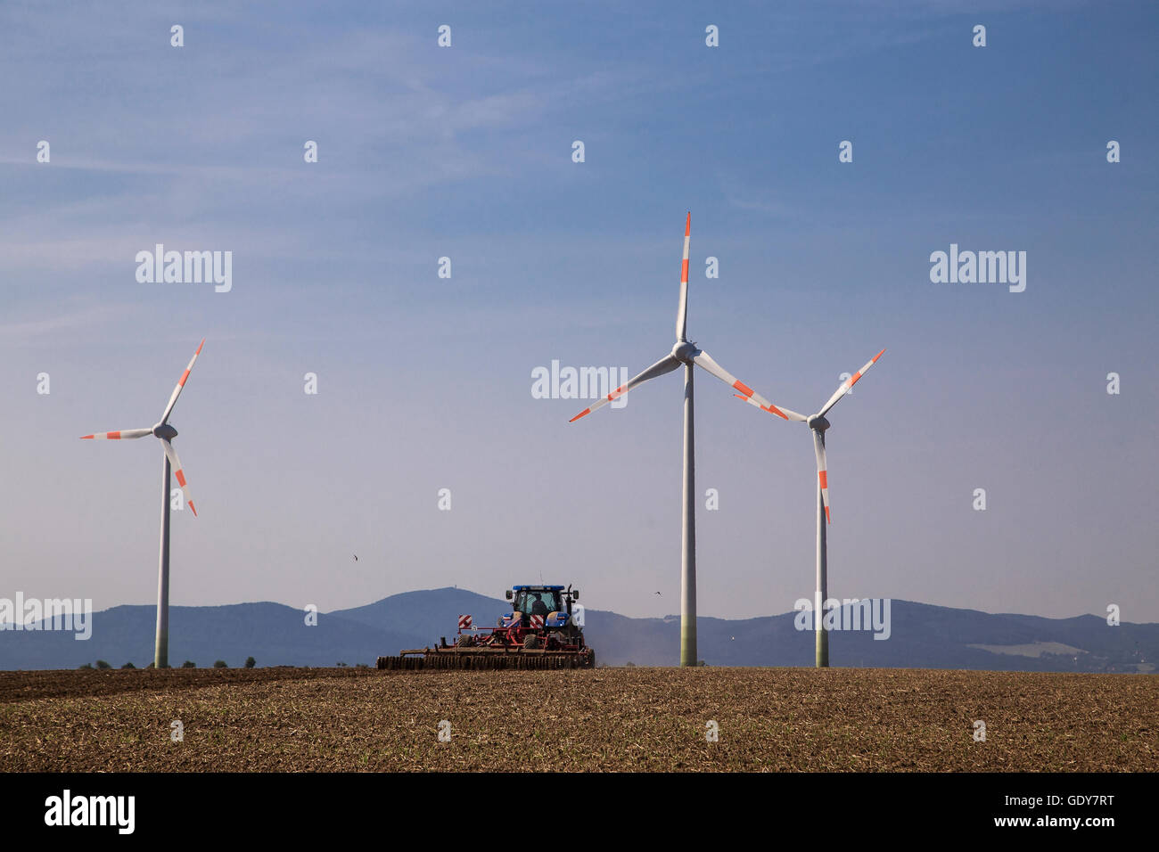 Mulini a vento in un campo di agricoltori, agricoltore aratura del suo campo Foto Stock