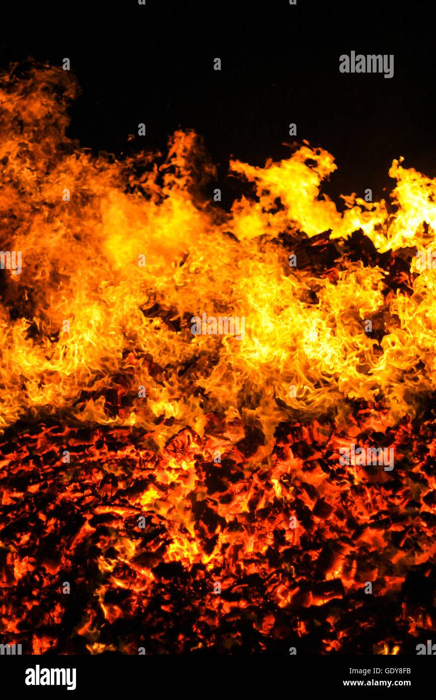 Immagine ravvicinata di un fuoco ardente set contro uno sfondo nero, rosso tizzi caldi nel fondo Foto Stock