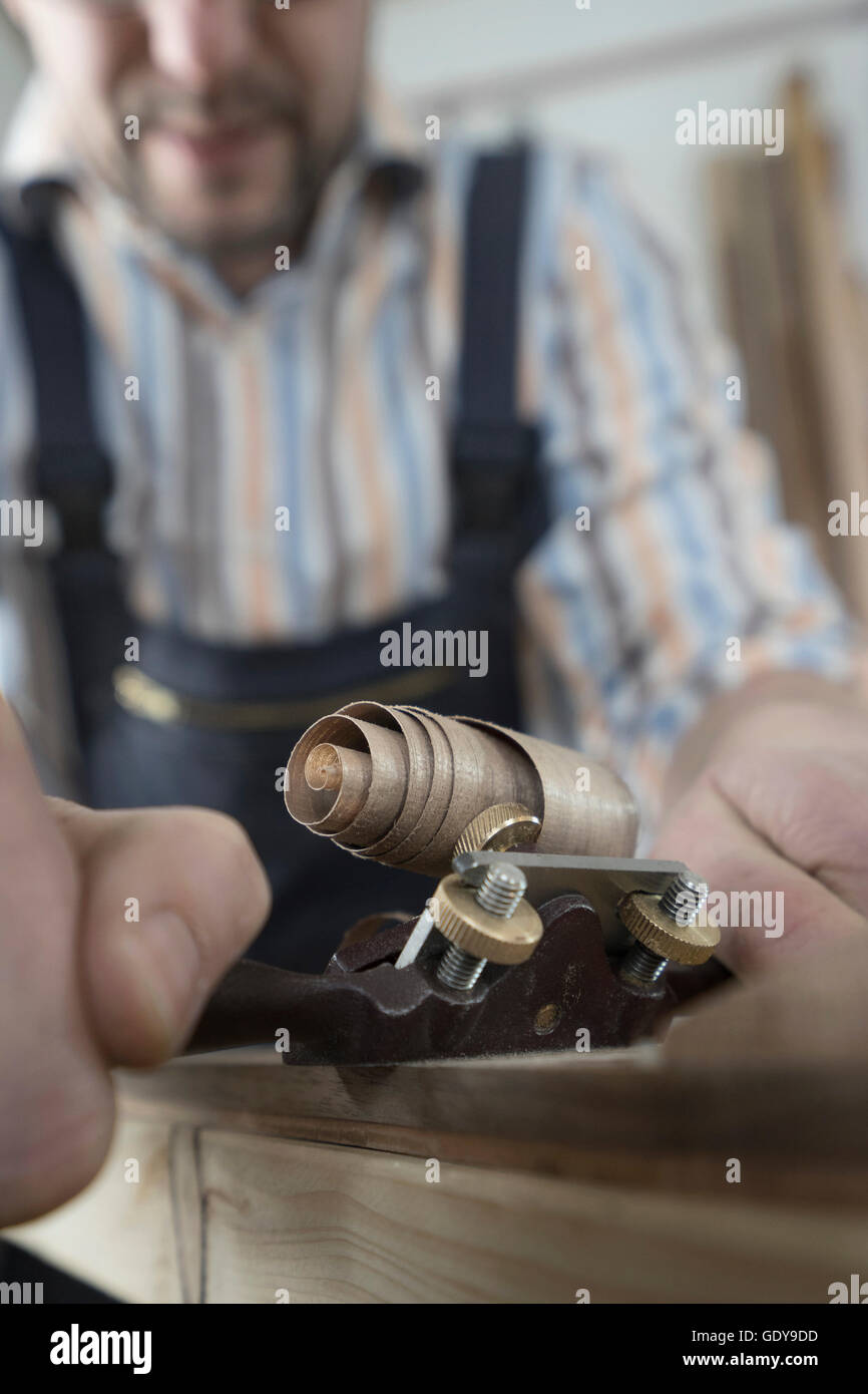 Maschio di bow maker legno di rasatura e dandogli una forma di prua in officina, Baviera, Germania Foto Stock