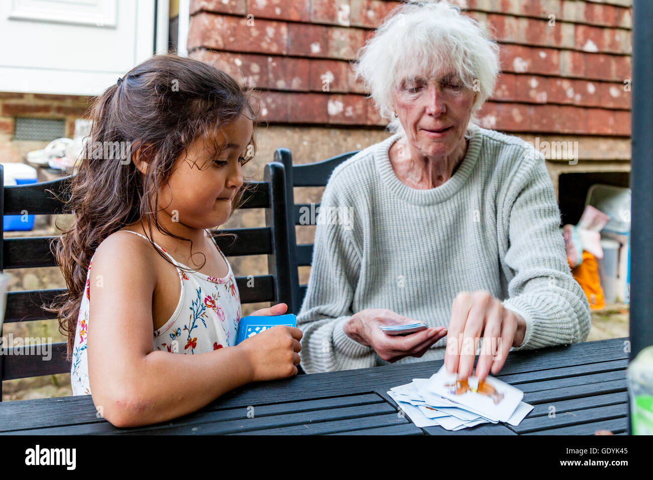 Una razza mista bambino gioca Snap con sua nonna, Sussex, Regno Unito Foto Stock