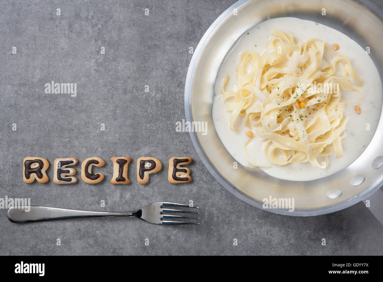 Parola tipografici della ricetta fatta di alfabeto i cookie con la forcella e una ciotola di tagliatelle Foto Stock