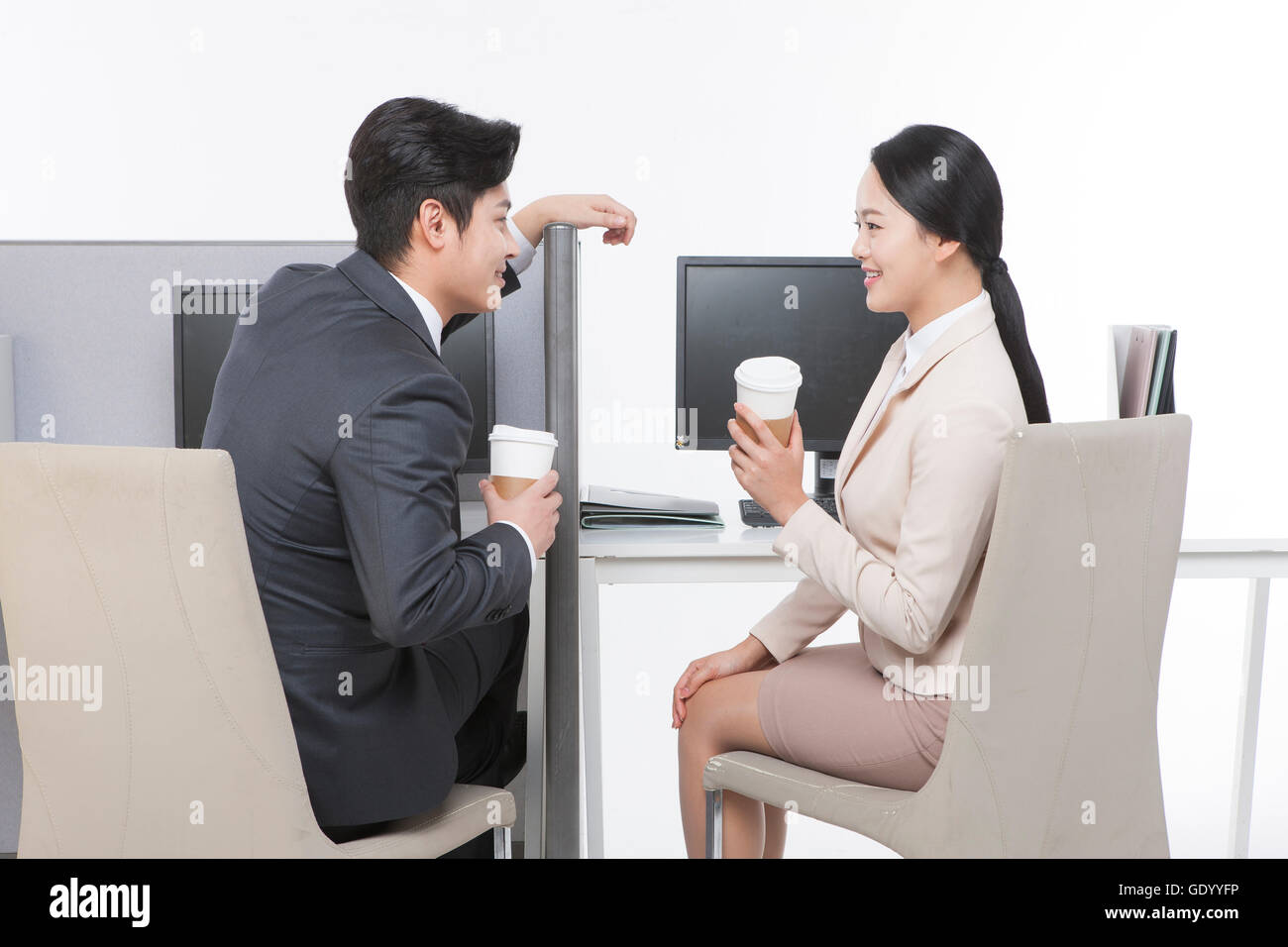 Sorridente giovane uomo di affari e business donna con caffè asporto faccia a faccia sul posto di lavoro Foto Stock