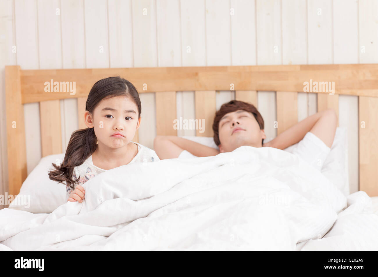 Annoiato figlia e padre dormire in un letto Foto Stock