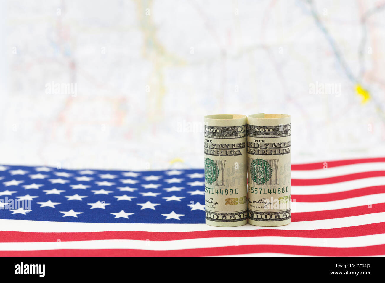Dollari americani posto sulla bandiera degli Stati Uniti con mappa distanti come sfondo. La crescita economica è una questione nazionale. Foto Stock