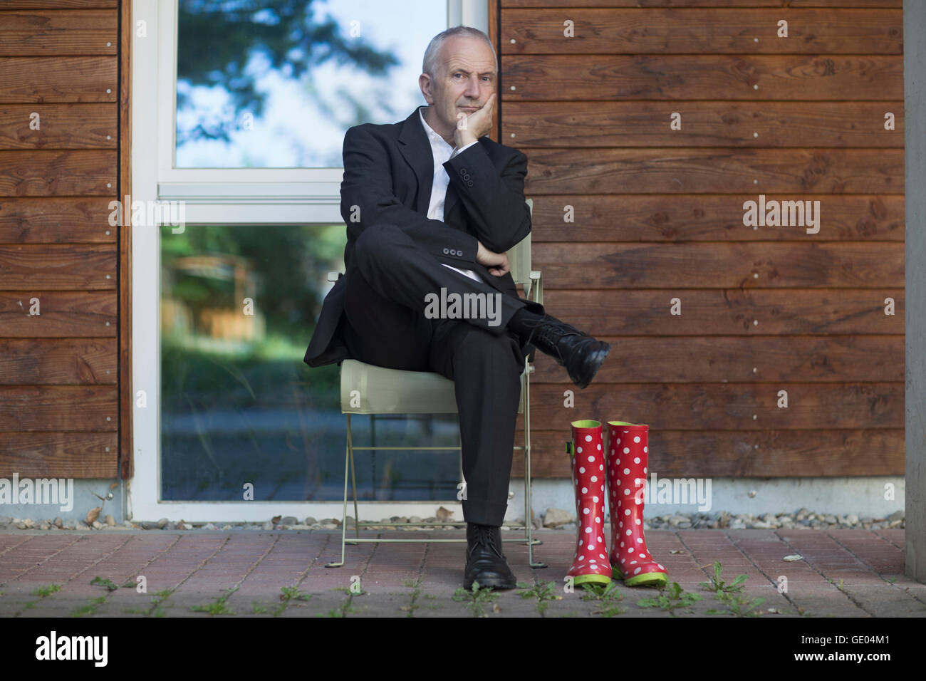 Considerato imprenditore senior indossare tuta e seduta a street, Freiburg im Breisgau, Baden-Württemberg, Germania Foto Stock