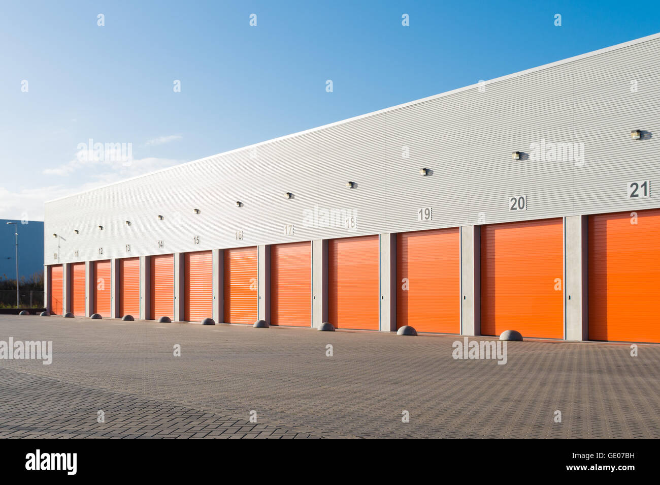Esterno di un magazzino commerciale con rullo arancione porte Foto Stock