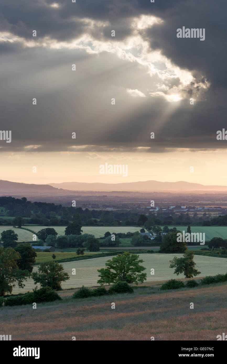 Vista su terreni agricoli e Vale of Evesham con Bredon Hill e Malvern Hills in distanza al tramonto Foto Stock