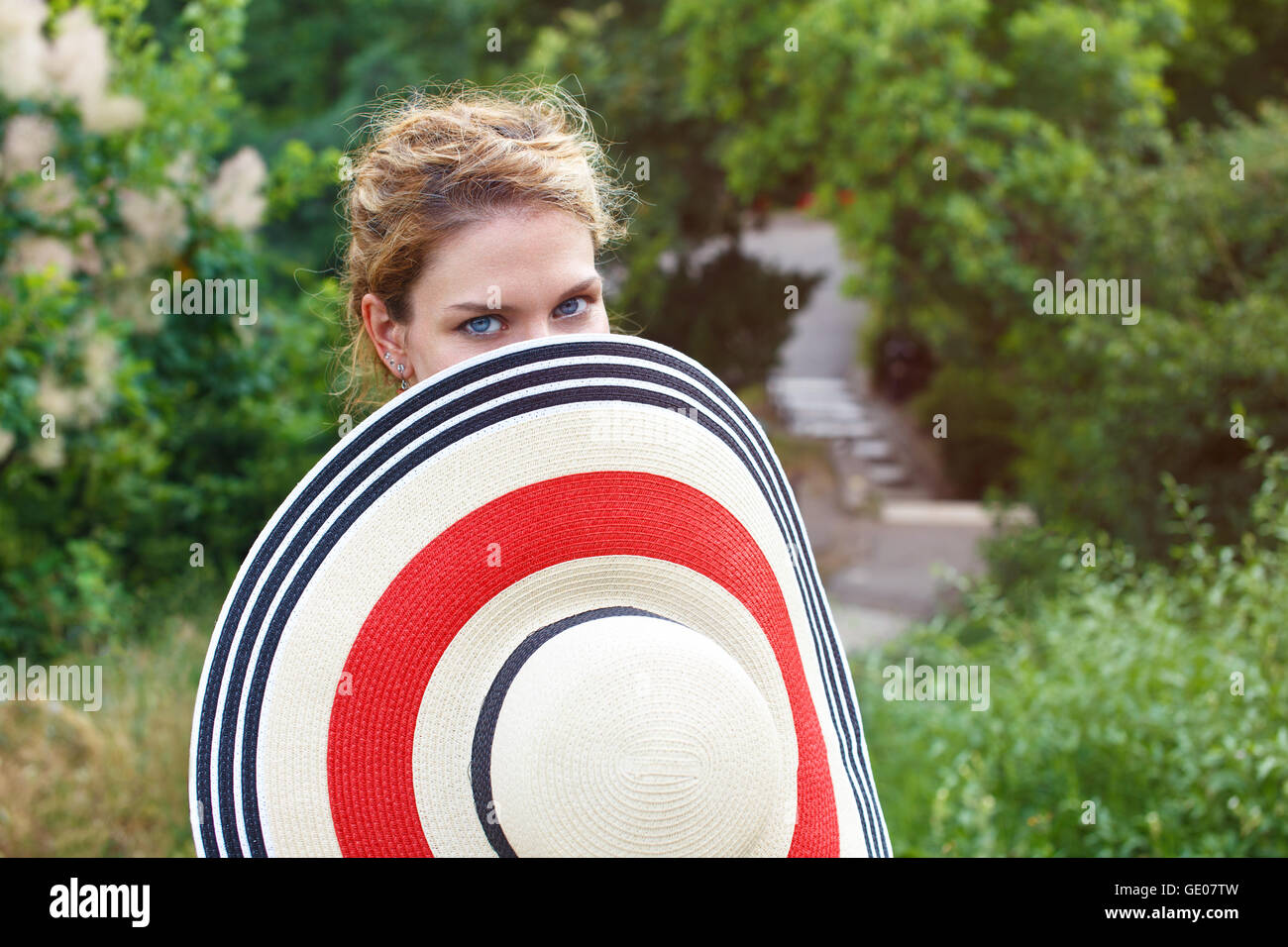 Donna che ricopre la faccia dietro hat outdoor Foto Stock