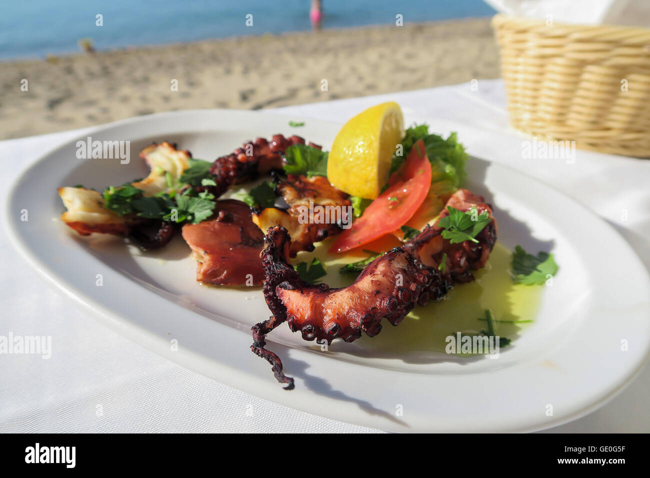 Polpo alla griglia con olive e una fetta di limone su una piastra dal mare. Foto Stock