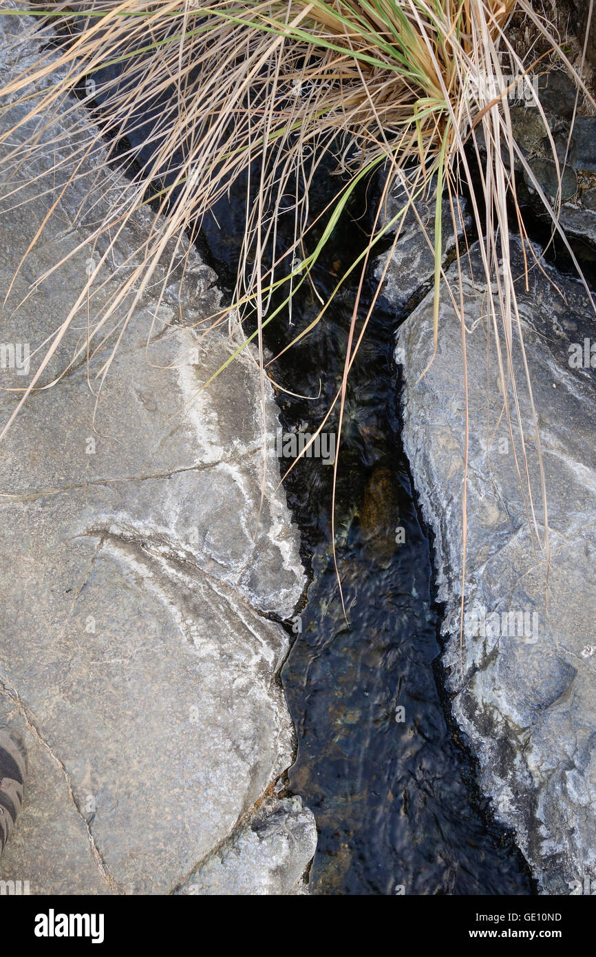 Piccolo ruscello di montagna si trova in modo attraverso due massi di roccia. Spagna. Foto Stock