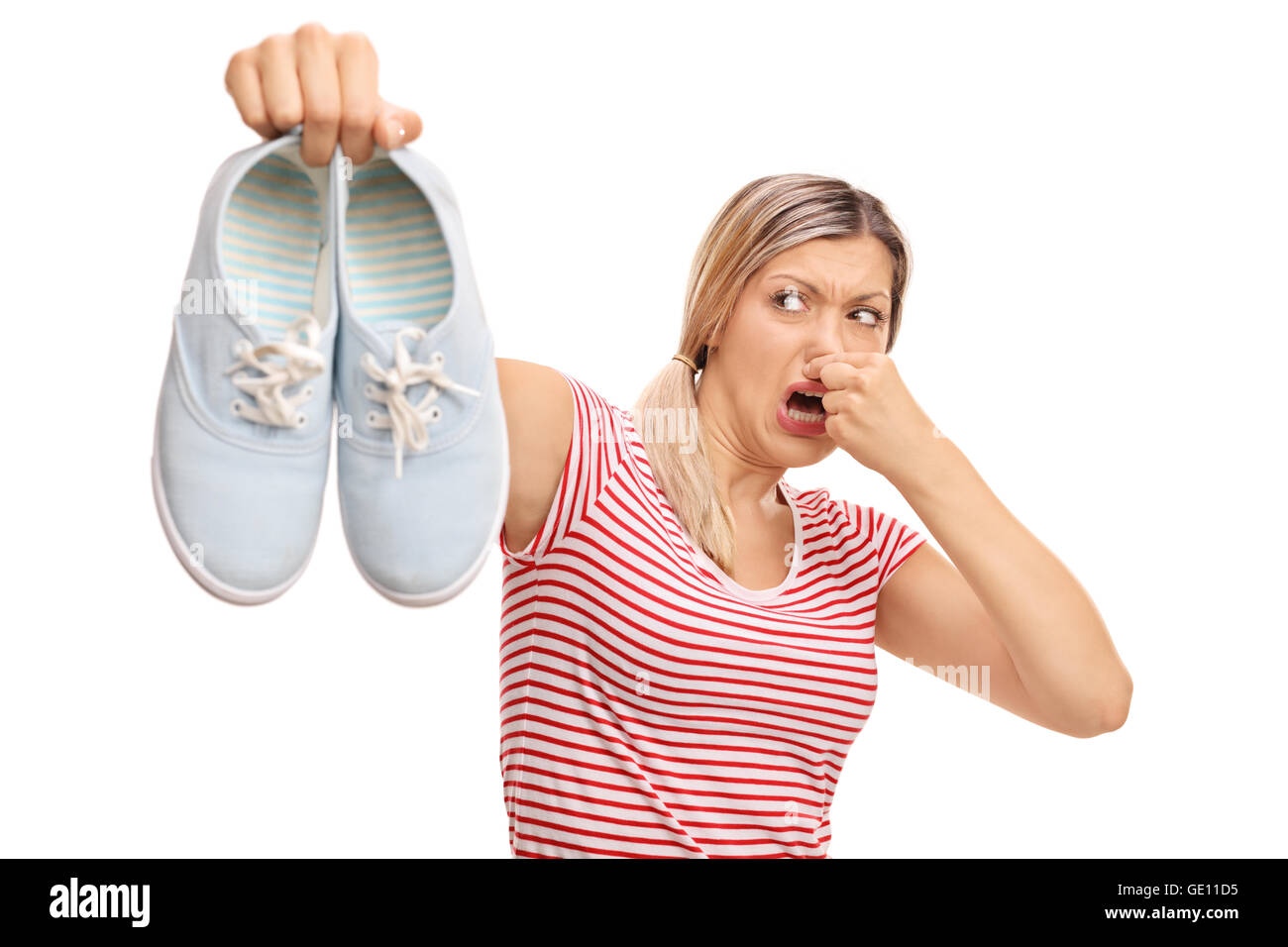 Disgustato donna tenendo un paio di scarpe stinky isolati su sfondo bianco Foto Stock