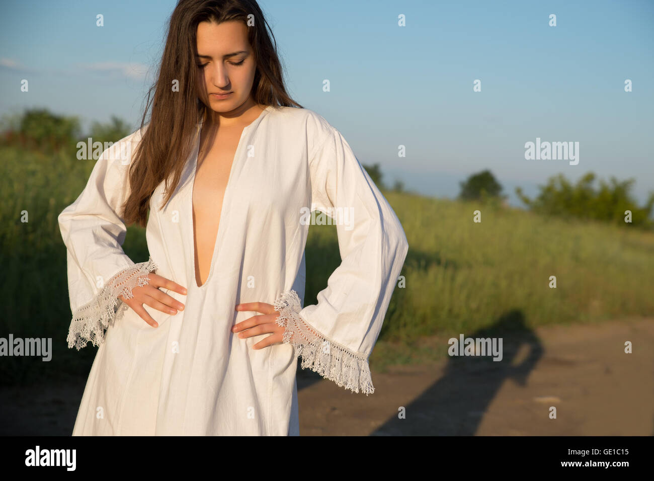 Donna in piedi nel campo in abito bianco Foto Stock