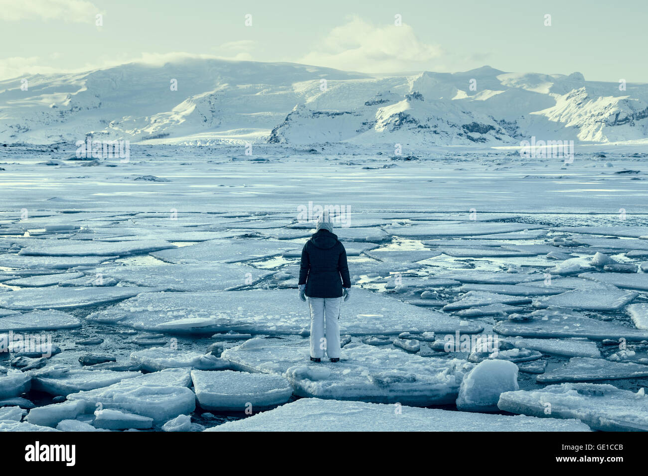 Donna in piedi sul ghiaccio floe sul lago ghiacciato, Islanda Foto Stock