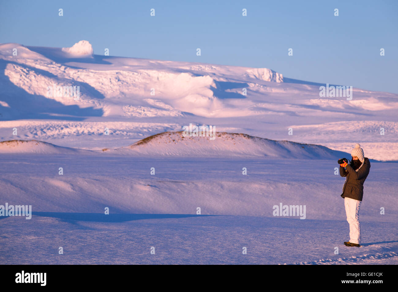 Donna di scattare una foto nel paesaggio invernale, Islanda Foto Stock
