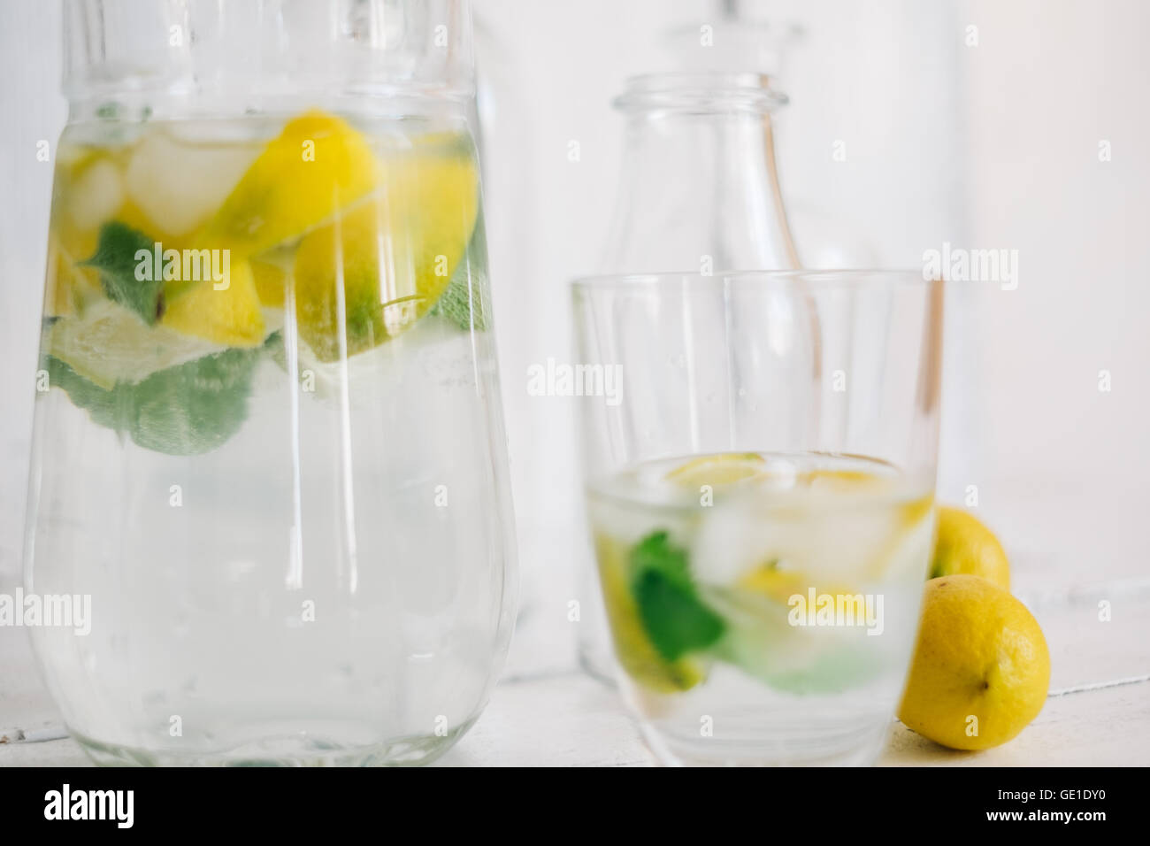 Il vetro e la brocca di acqua con limone fresco, calce, menta e cubetti di ghiaccio Foto Stock