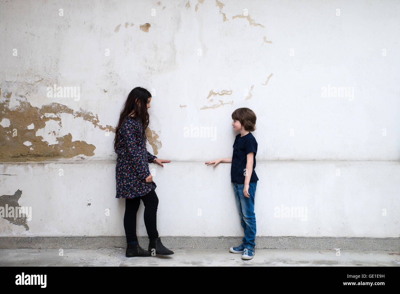 Un ragazzo e una ragazza in piedi dalla parete guardando ogni altro Foto Stock