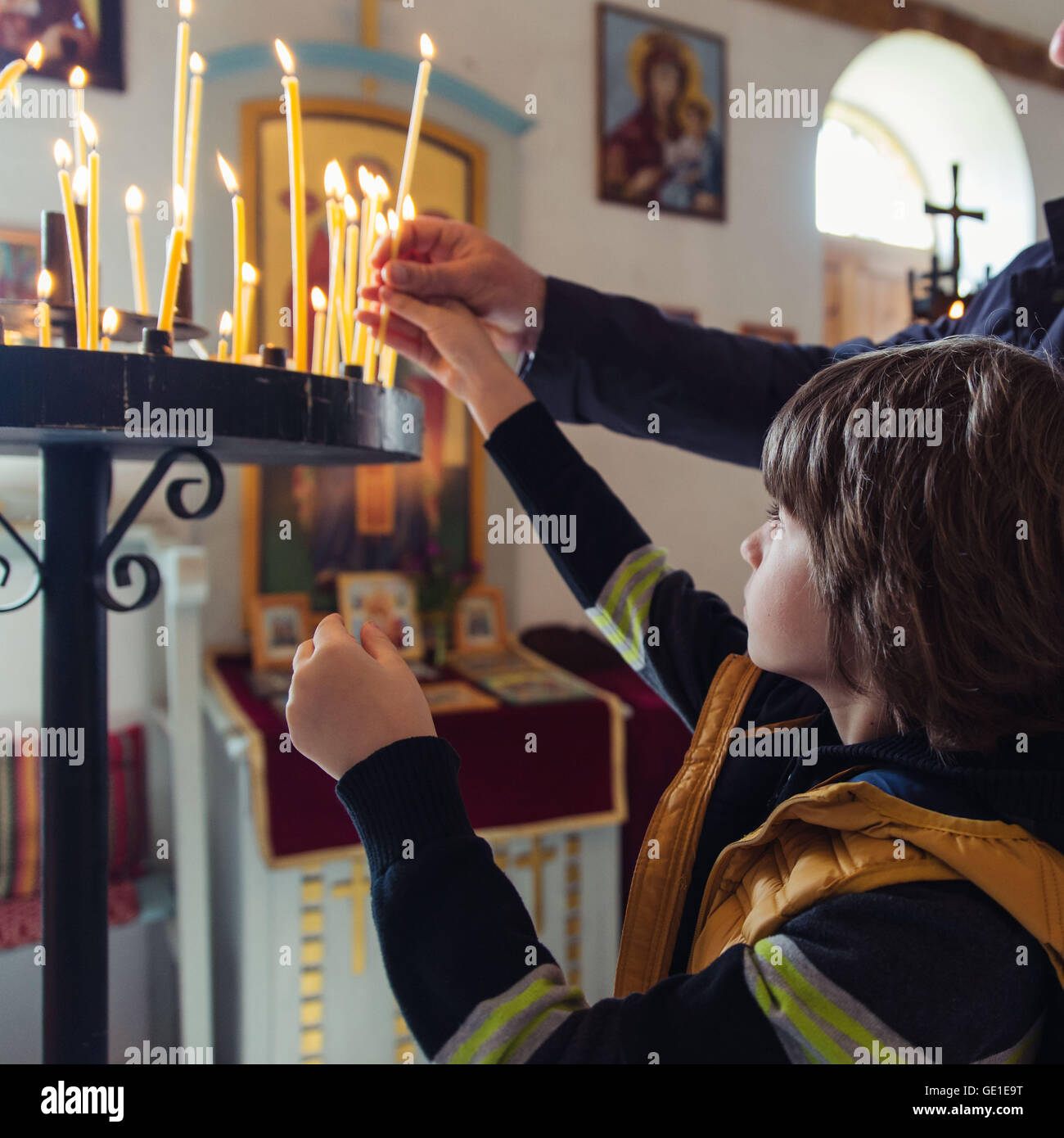 Ragazzo lightning candele in una chiesa Foto Stock