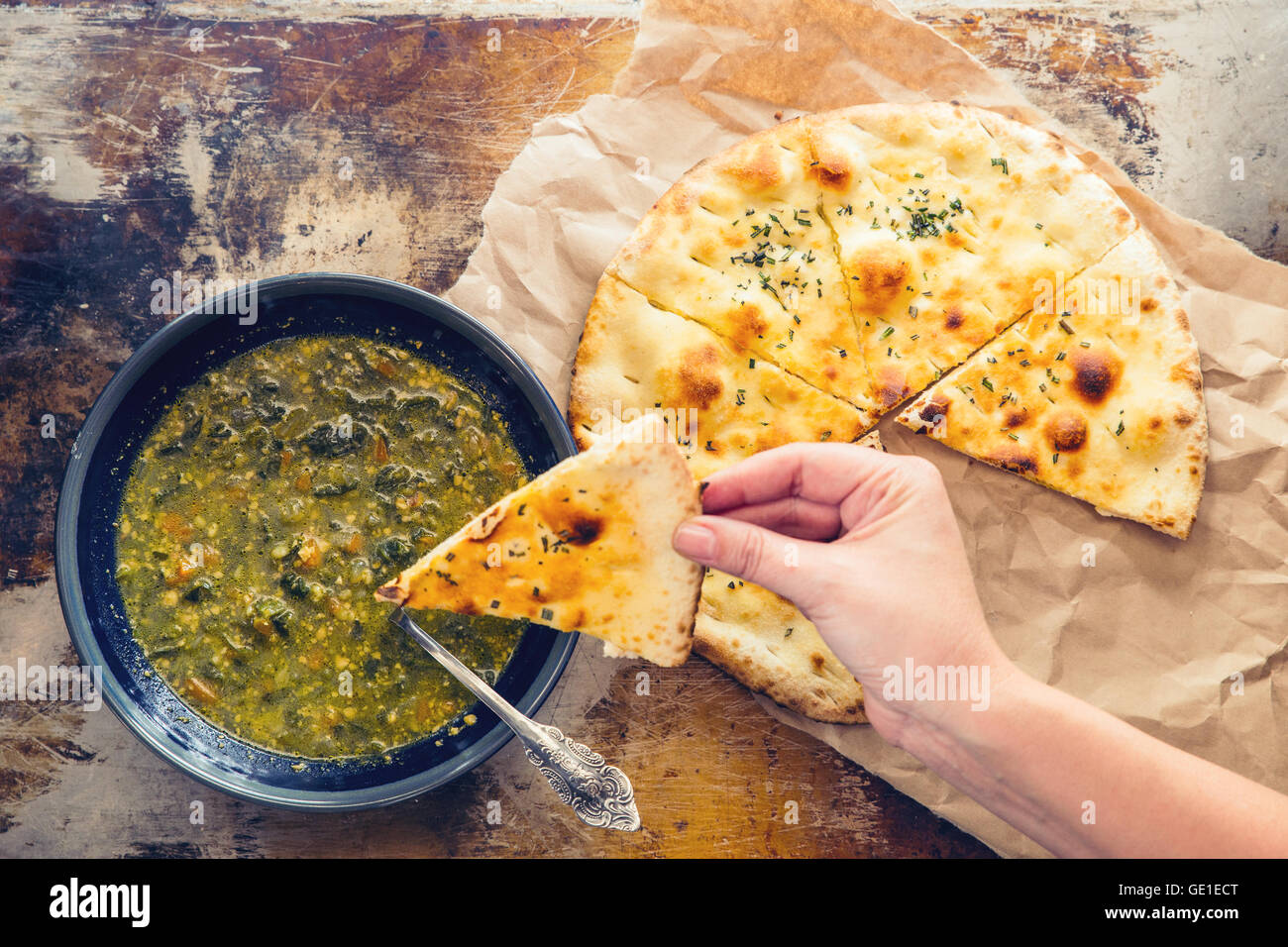Mano intingere il pane nella ciotola di zuppa Foto Stock