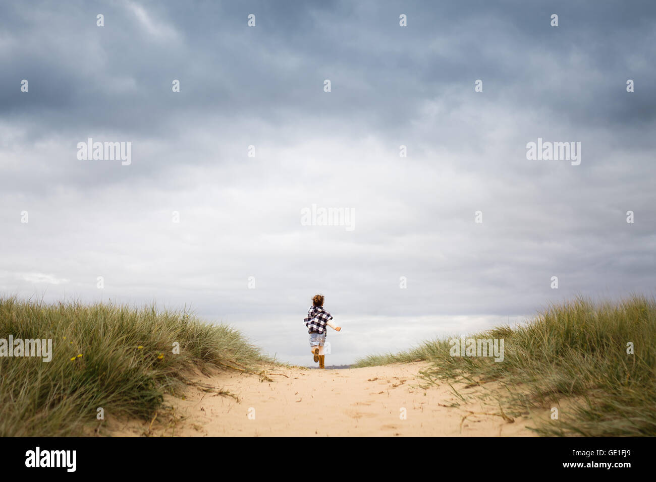 Ragazza che corre attraverso le dune di sabbia verso la spiaggia Foto Stock Ragazza che corre attraverso le dune di sabbia verso la spiaggia Foto Stock