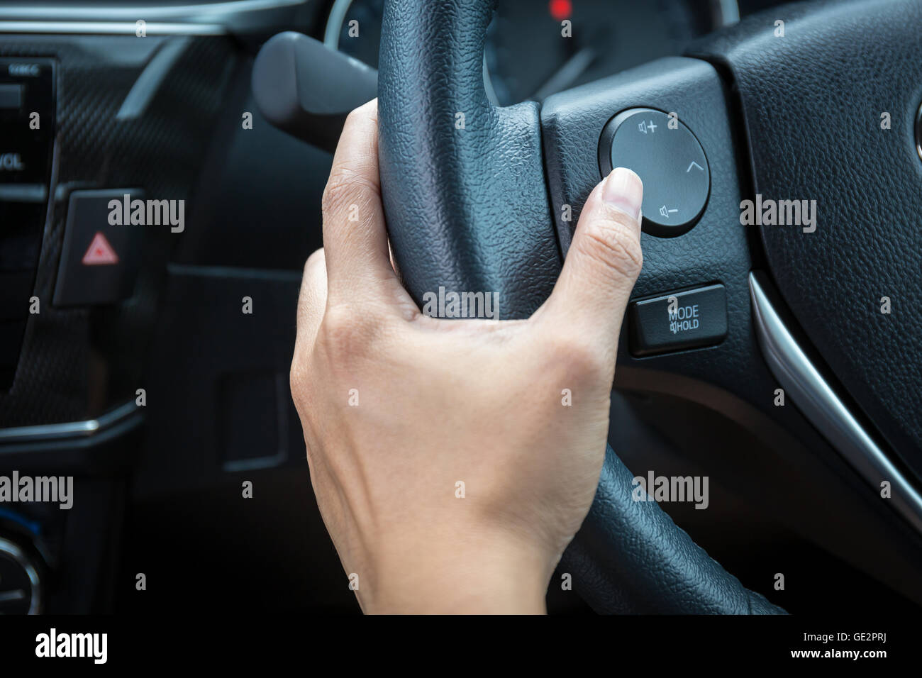 Una donna mano spinge il pulsante di controllo del volume su un volante. Foto Stock