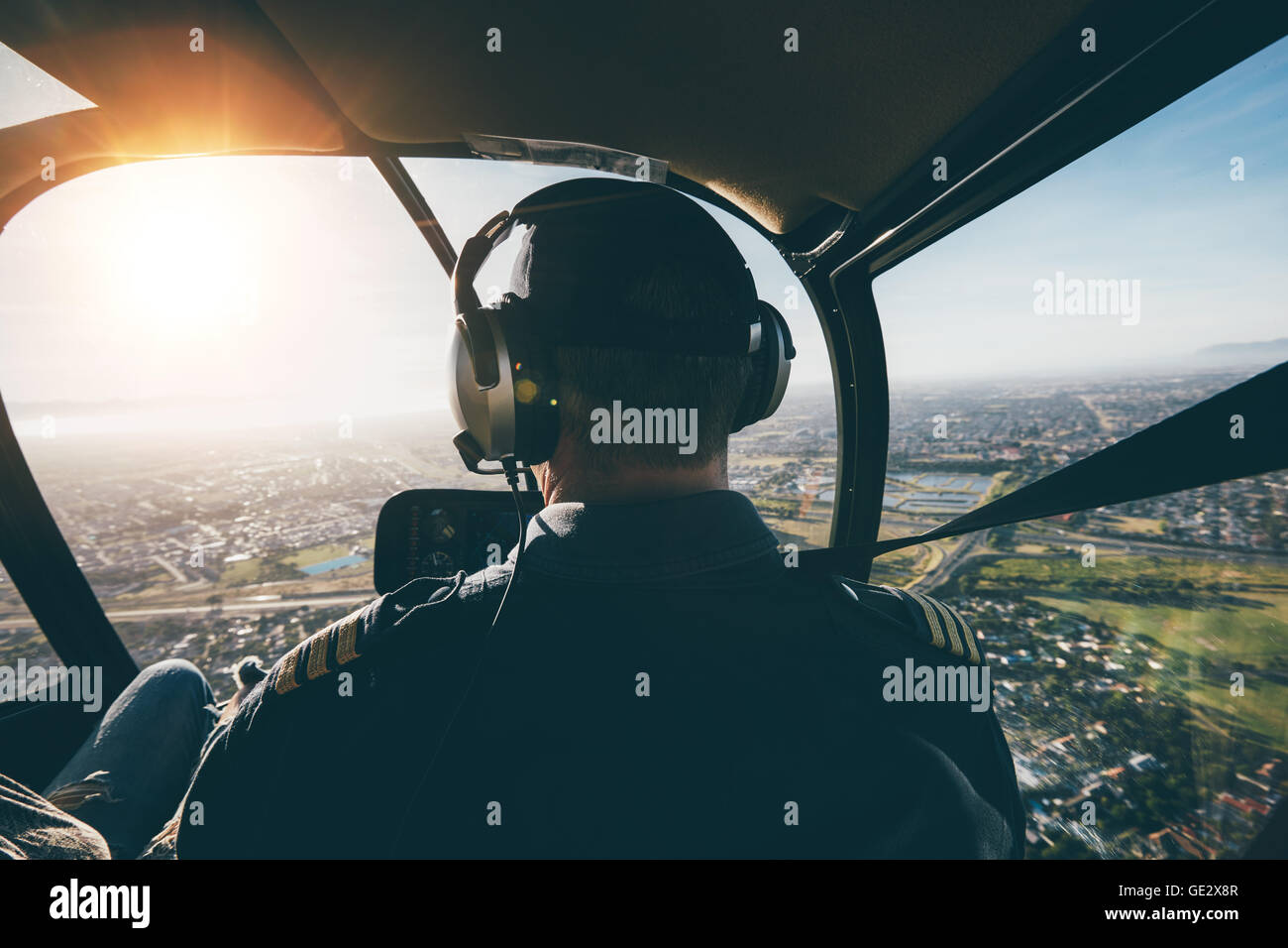 Vista posteriore di un maschio di pilota di volare in elicottero sulla giornata di sole. Foto Stock