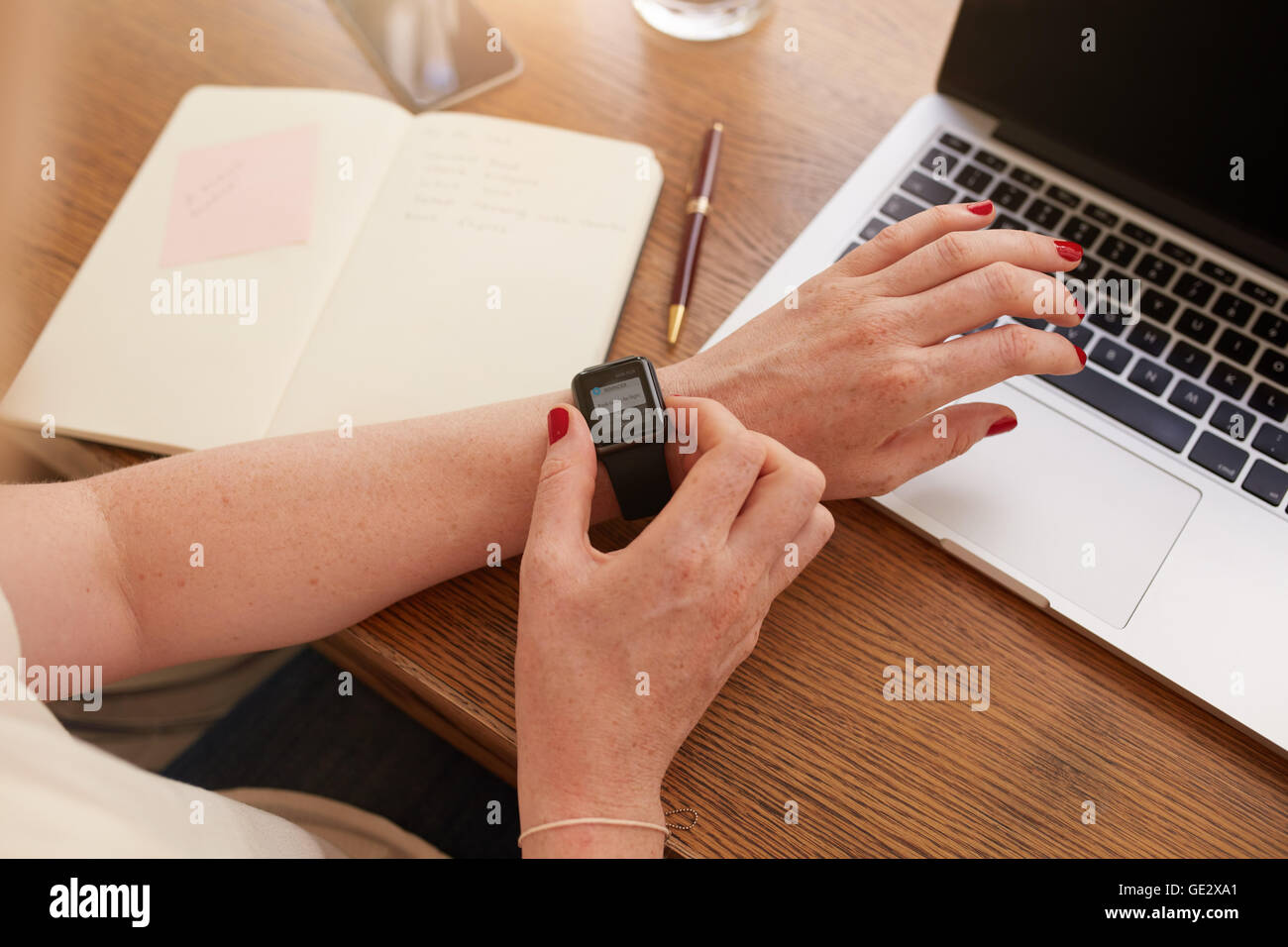 Close up smartwatch sulla donna la mano, ella è utilizzando la smart orologio da polso mentre è seduto alla sua scrivania. Foto Stock