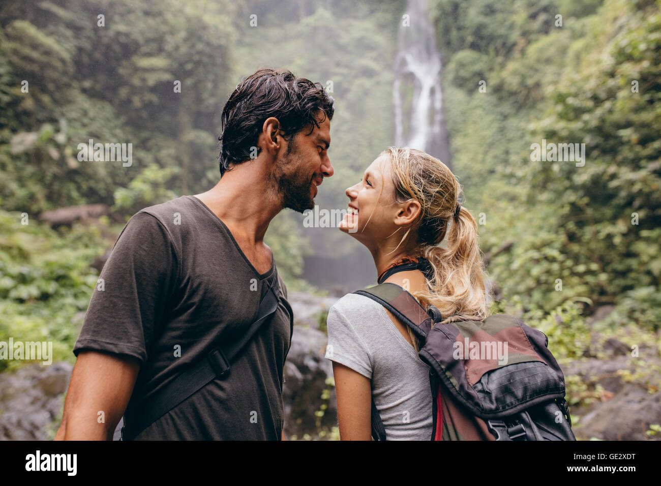 Affettuosa coppia giovane insieme sulla passeggiata. Giovane uomo e donna con zaino guardando ogni altro e sorridente. Escursionismo in fores Foto Stock